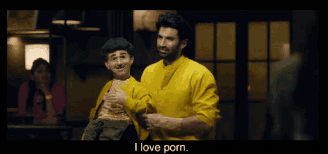 a man in a yellow shirt is holding a boy in his arms and says i love porn