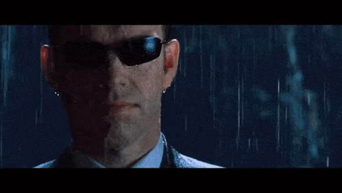 a man in a suit and sunglasses is standing in the rain