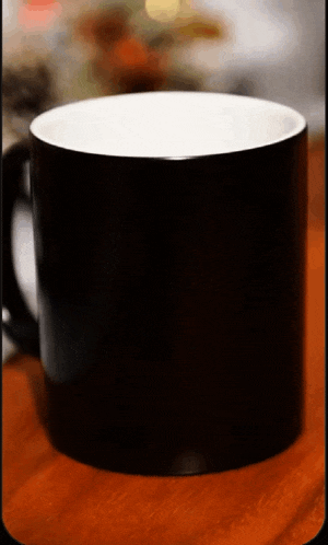 a black coffee mug with a white rim sits on a wooden table