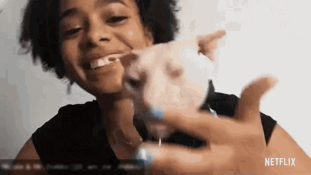 a woman is holding a small white dog in her hand .