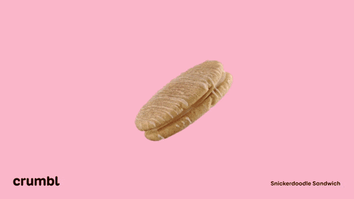 a close up of a cookie with white frosting on a pink surface