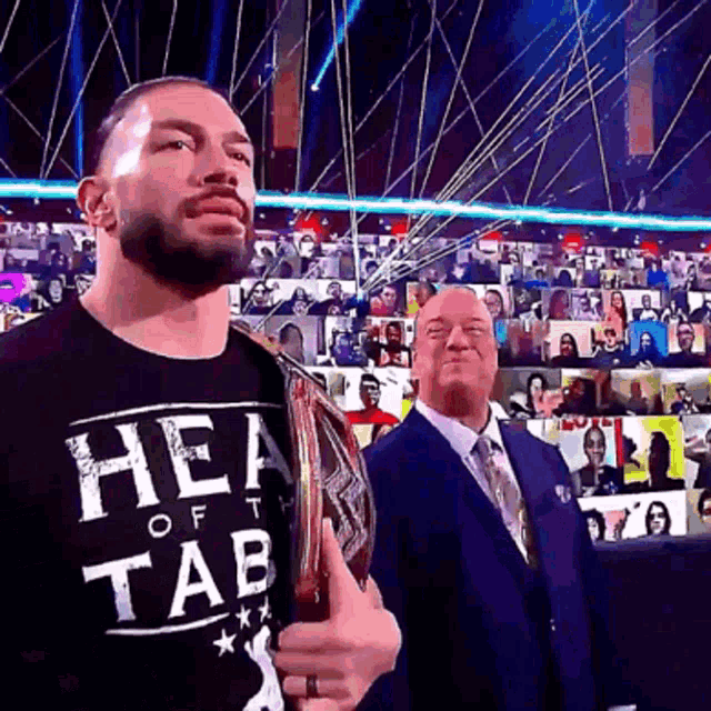 a man wearing a shirt that says hea of tab holds a trophy