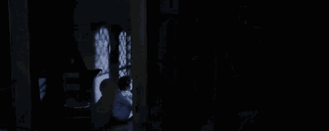 harry potter is sitting on the floor in a dark room with a window .