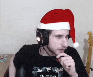a man wearing a santa hat and headphones is sitting in front of a guitar