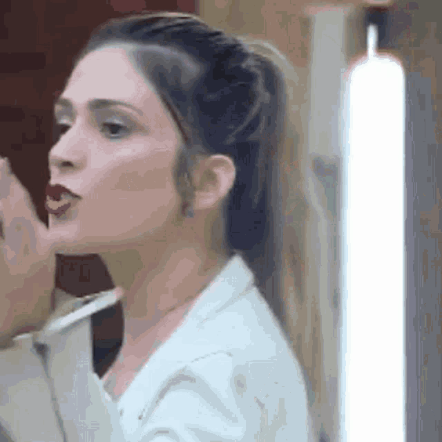 a woman is applying lipstick in front of a mirror in a room .