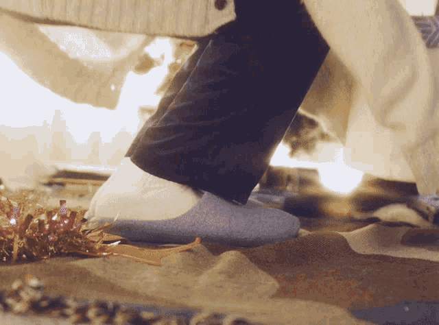 a person wearing blue slippers is standing on a rug