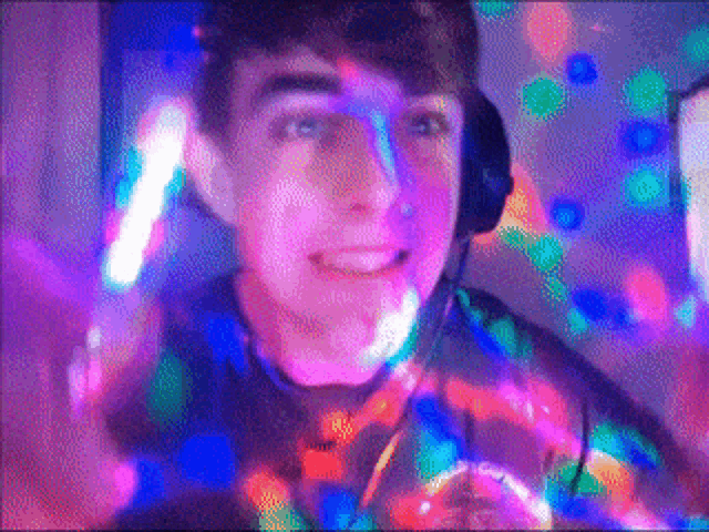 a young man wearing headphones is smiling in front of a disco ball