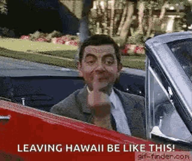 a man in a suit and tie is driving a red car and making a funny face .