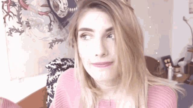 a woman in a pink sweater is making a face