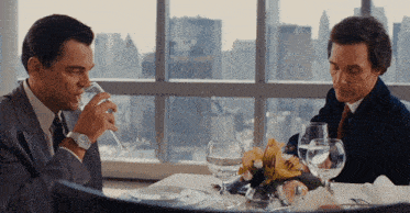 two men sit at a table drinking water