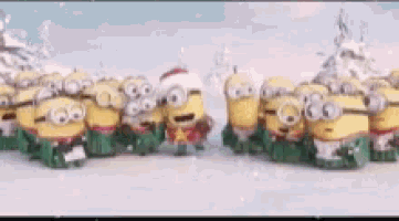a group of minions are standing in the snow wearing christmas costumes .