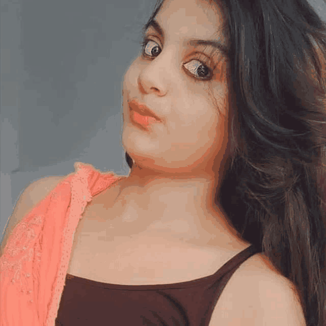 a close up of a woman 's face wearing a black tank top and a pink saree .