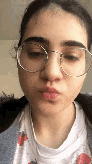 a young woman wearing glasses and a strawberry shirt