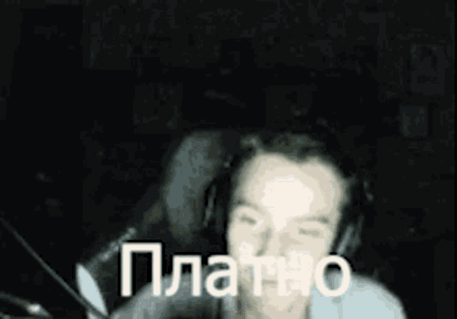 a man wearing headphones is sitting in a chair in a dark room and making a funny face .