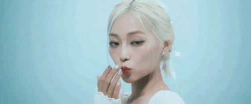 a close up of a woman blowing a kiss with her hand against a blue background .