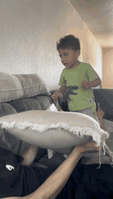 a boy wearing a green shirt with a dinosaur on it