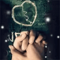 a couple of hands holding each other in front of a broken heart drawn on a wall .