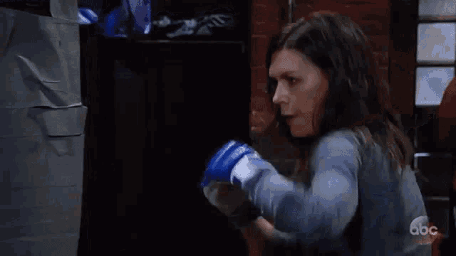 a woman wearing boxing gloves is kicking a man in the face in a gym .