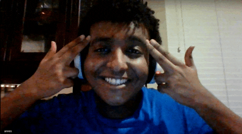 a young man wearing headphones is smiling and giving the peace sign