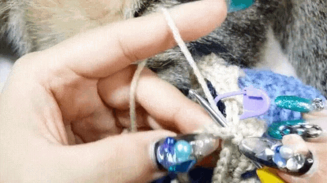 a close up of a person holding a crochet hook and yarn .