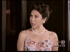 a woman wearing a floral dress and a pearl necklace is on a television screen