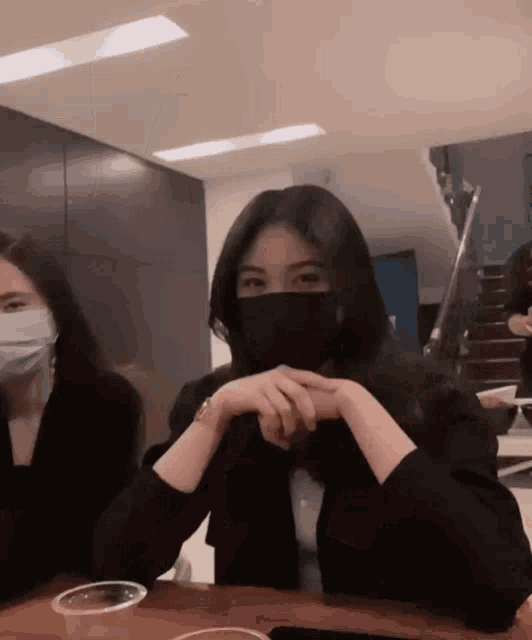 a woman wearing a face mask sits at a table