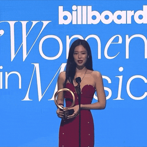 a woman in a red dress stands in front of a billboard that says " women in music "