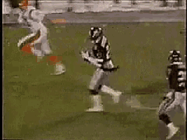 a football player is jumping in the air to catch a ball while another player tries to stop him .