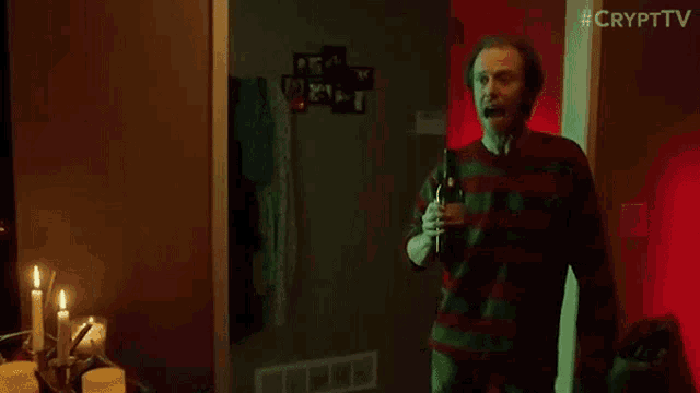 a man in a plaid sweater is holding a bottle of wine in a dark room .