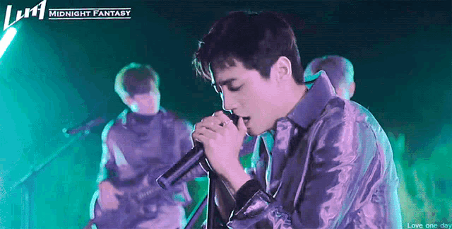 a man is singing into a microphone on a stage in front of a midnight fantasy logo