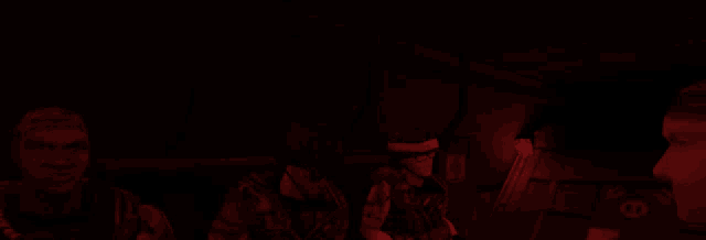 a group of people are sitting in a dark room with a red light shining on them