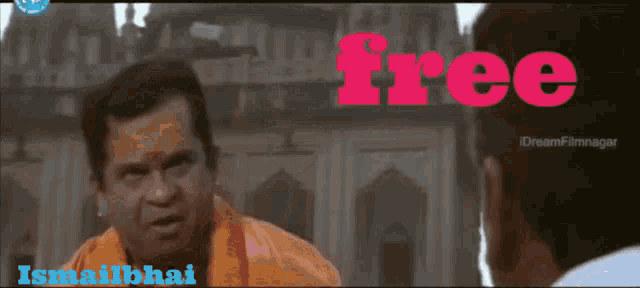 a man in an orange turban talks to another man in front of a building with the word free above him