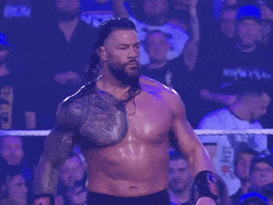 a shirtless wrestler is standing in front of a crowd with a shirt that says ' smackdown ' on it