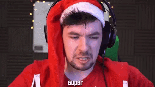 a man wearing headphones and a santa hat has the word super on his face .