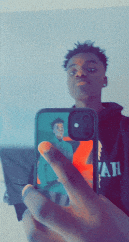 a young man taking a picture of himself with a phone that says ' ah ' on the front