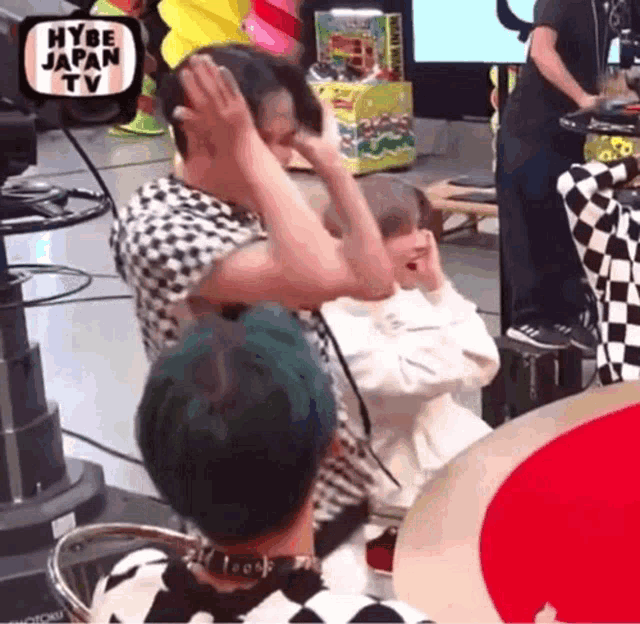 a couple of people are standing in front of a camera with the words hybe japan tv on it