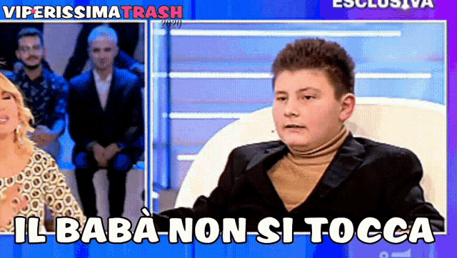 a man in a suit and turtleneck sits in a chair with the words il baba non si tocca below him