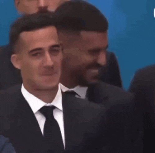 a man in a suit and tie is smiling in front of a crowd