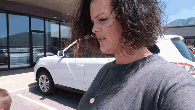 a woman stands in front of a white car that says ' no parking ' on the door