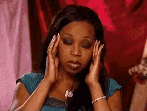 a woman is holding her head with her hands .
