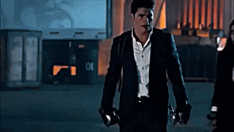 a man in a suit and white shirt is walking down a dark street .