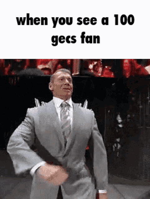 a man in a suit and tie is dancing in front of a crowd with the caption when you see a 100 gecs fan .