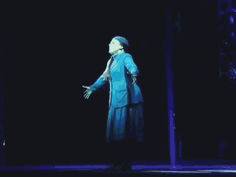 a woman in a blue dress is standing on a stage