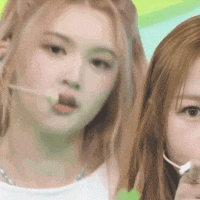 two women are standing next to each other and one is holding a lollipop in her mouth .