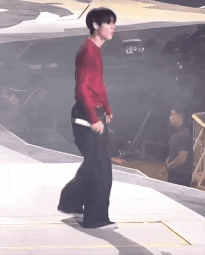 a man in a red shirt and black pants is standing on a stage