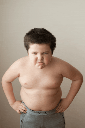 a young boy without a shirt is making a funny face