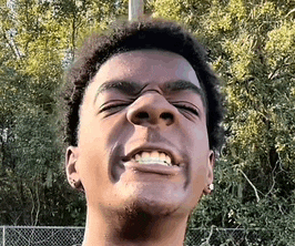 a close up of a young man making a funny face with his eyes closed .