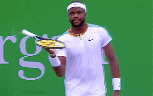 a man is holding a tennis racquet in front of a sign that says rgs