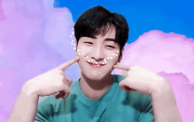 a young man in a green shirt is making a funny face with his fingers