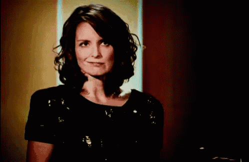 a woman in a black dress is smiling while standing in front of a wall .